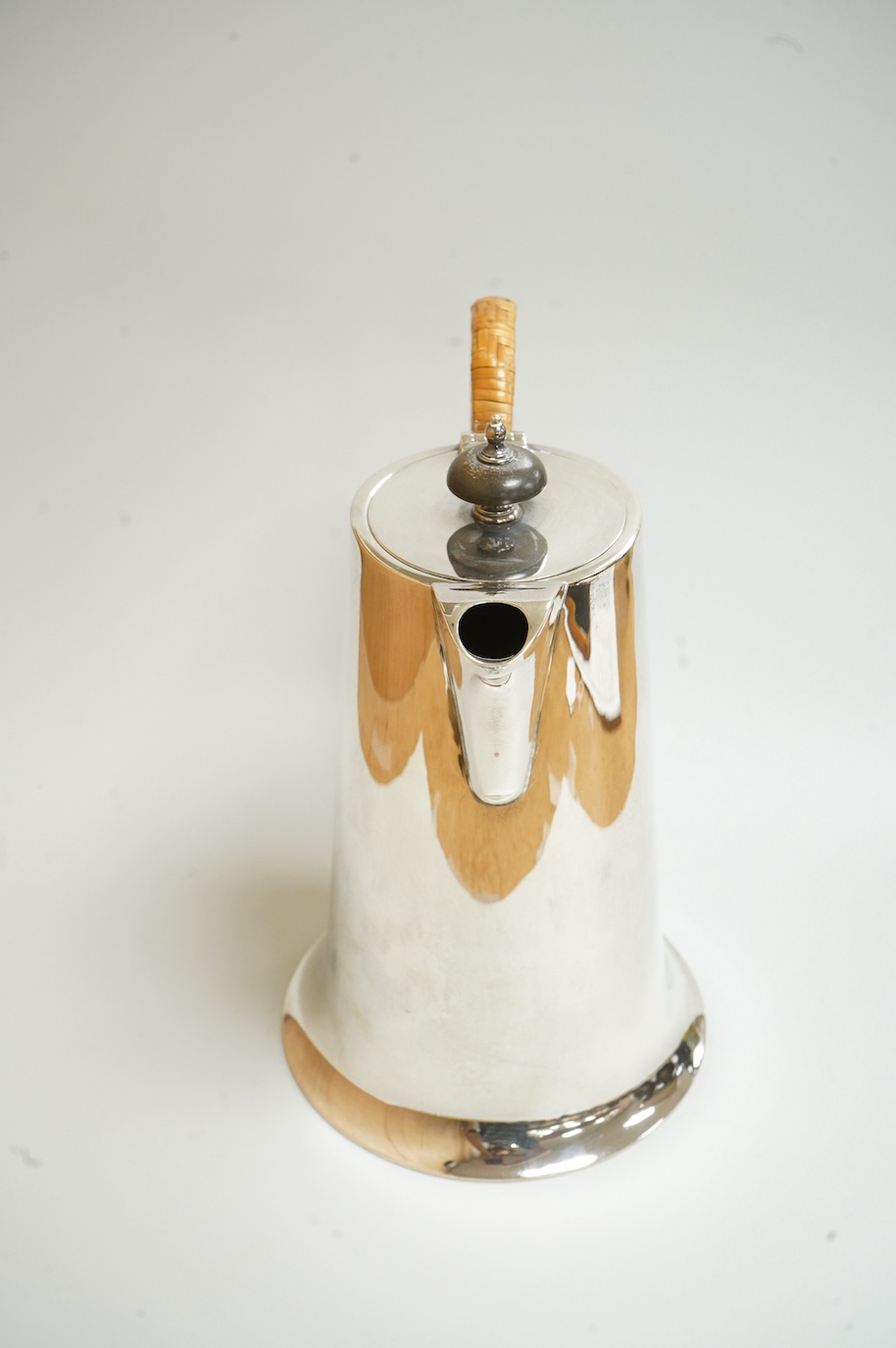 A George V silver hot water jug, by Walker & Hall, Sheffield, 1922, of tapering form, with rattan handle and circular spreading foot, height 22cm, 24.7oz.